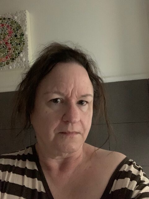 A white woman with brown hair wearing a striped shirt.