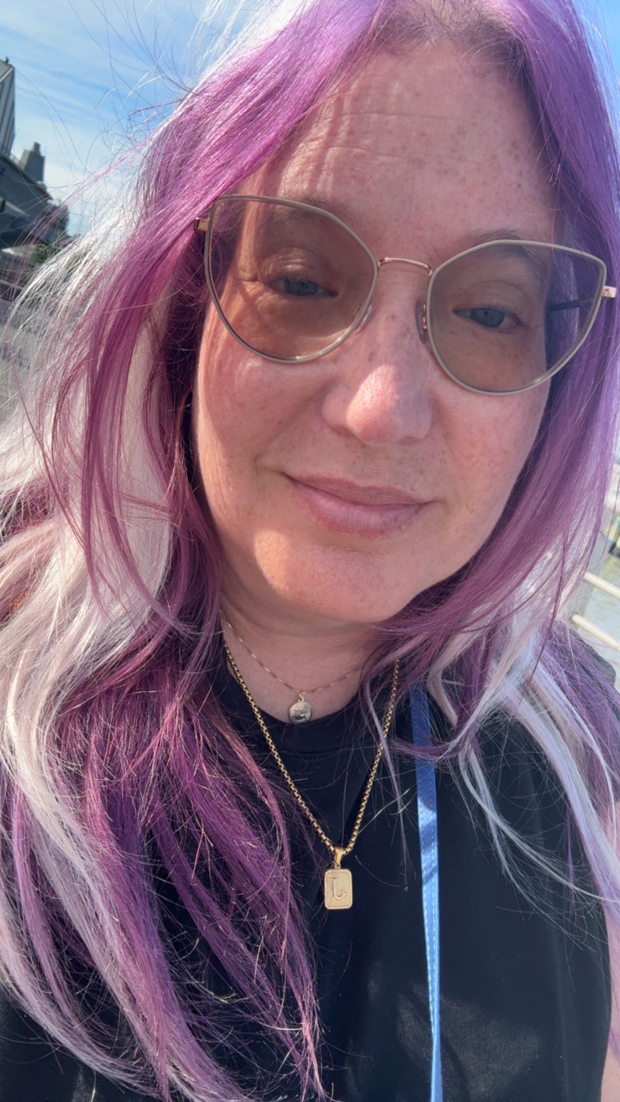 White woman with purple hair and glasses. 