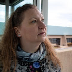 White woman with long red hair looking off camera. 